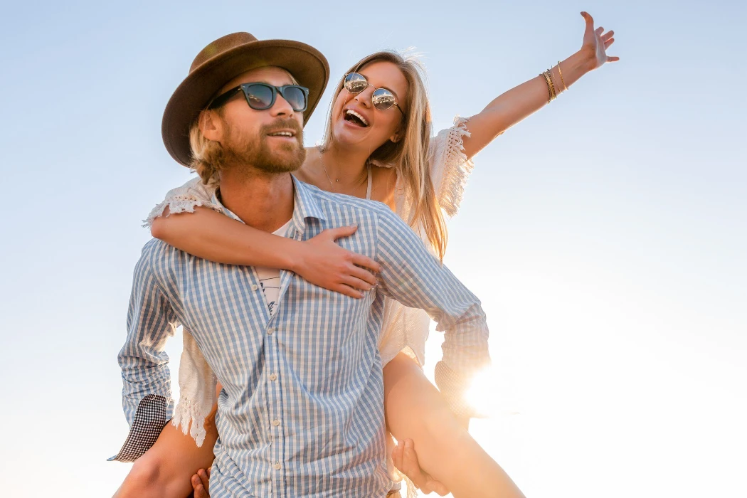 Attractive happy couple laughing traveling in summer by sea, man and woman wearing sunglasses